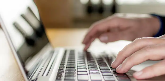 Close up of hands typing on a laptop.