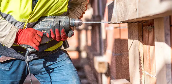 Construction worker drilling into a house.