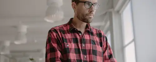 Man wearing plaid shirt tying at a computer.