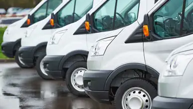 A fleet of white cargo fans parked in a lot.