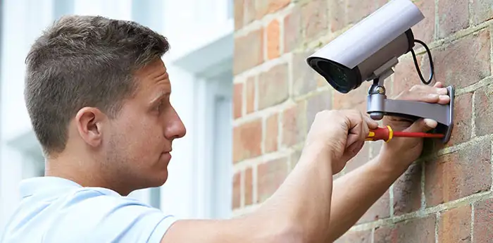 Man fixing a security camera outside a home.