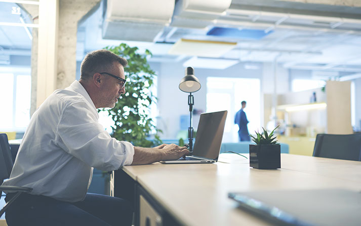 Man sitting at a desk working on on a laptop.