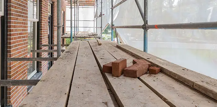 Bricks laying on scaffolding outside a brick building.