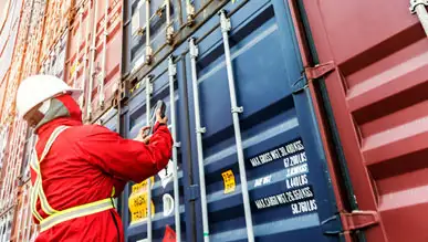 A worker opening a steel cargo box.