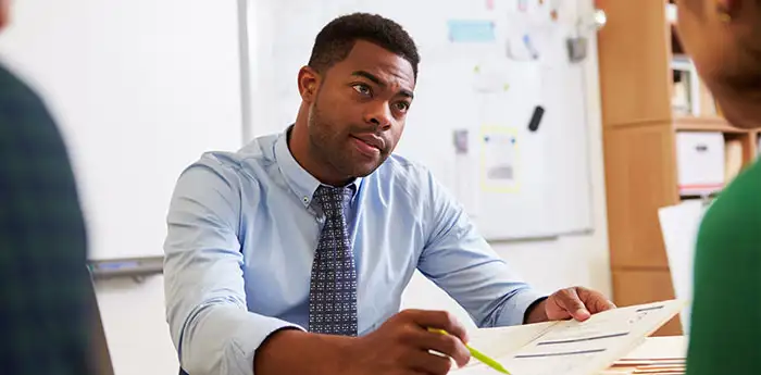 Business man holding a highlighter on a piece of paper.