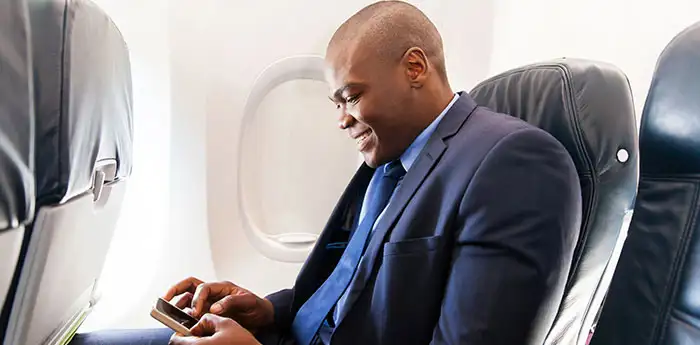 Businessman looking at his phone while on an airplane.