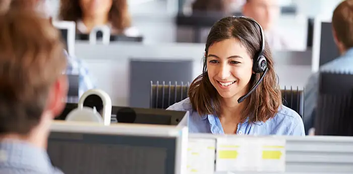 Woman speaking at her desk on a headset.